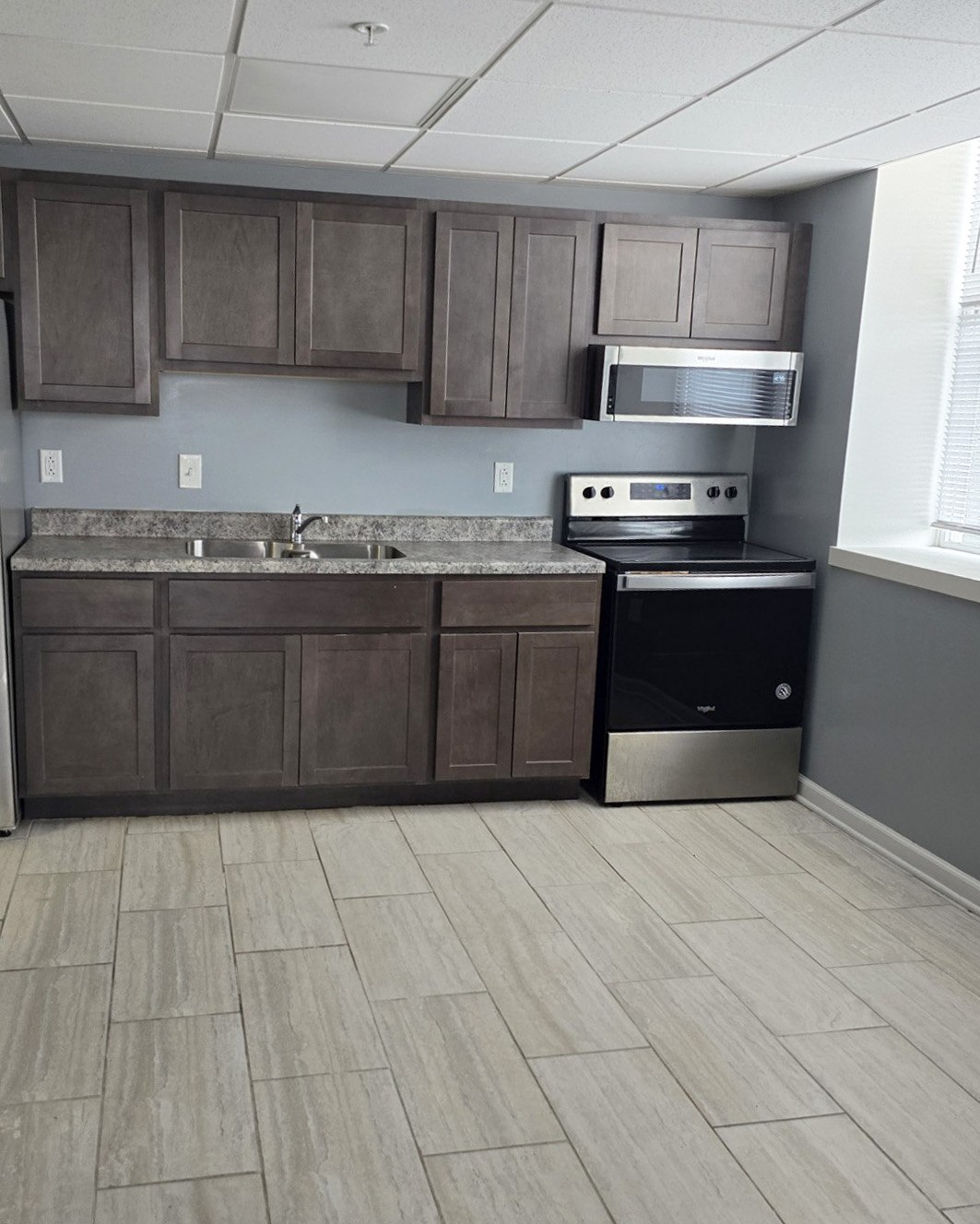 A kitchen with brown cabinets and a black dishwasher.